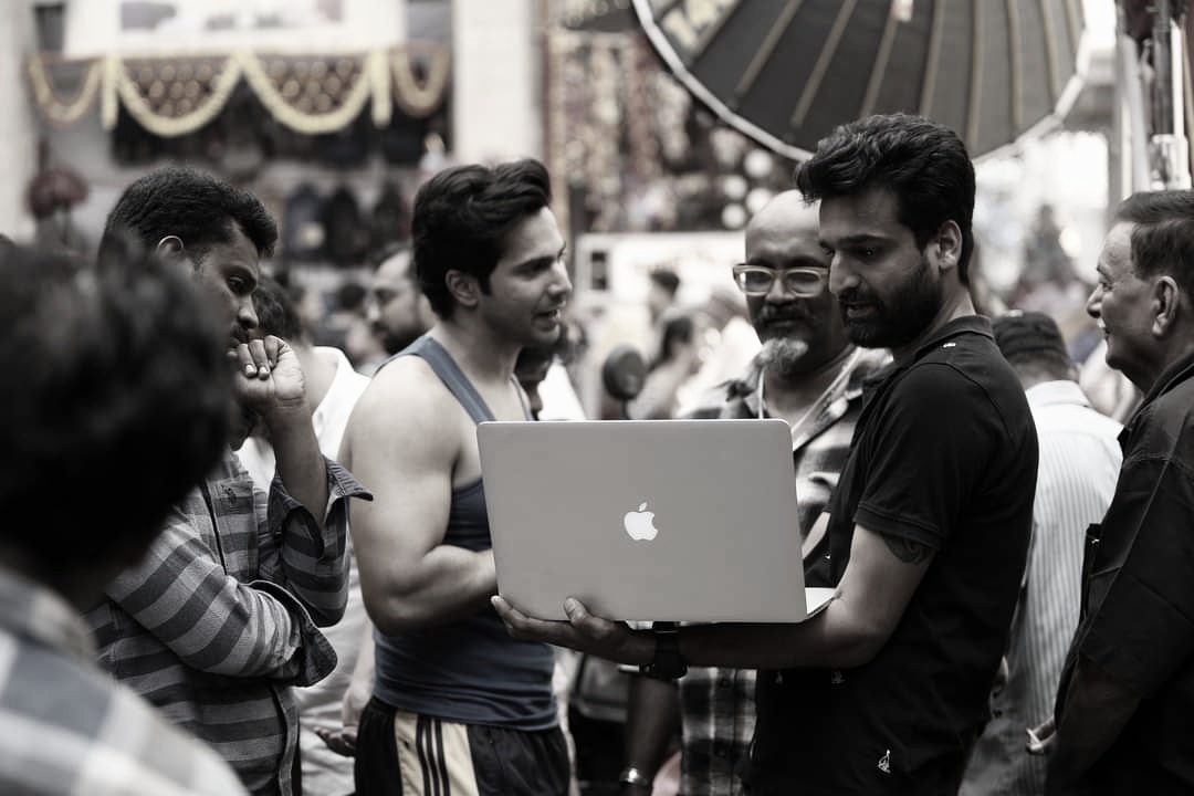 On-set collaboration: Film crew gathered around laptop reviewing dailies on location